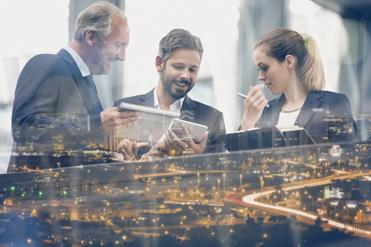 Top of image is 3 people talking in a meeting. Bottom of image is cityscape at night
