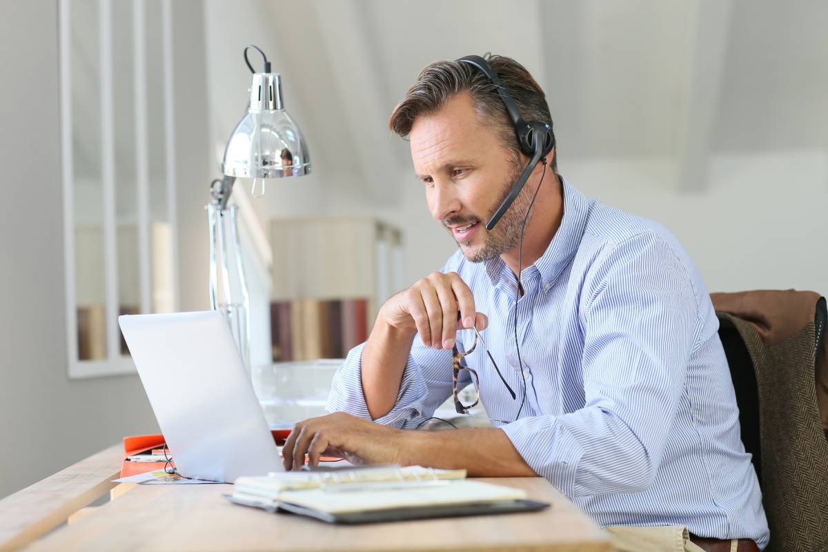 A man working from home using a laptop and a headset