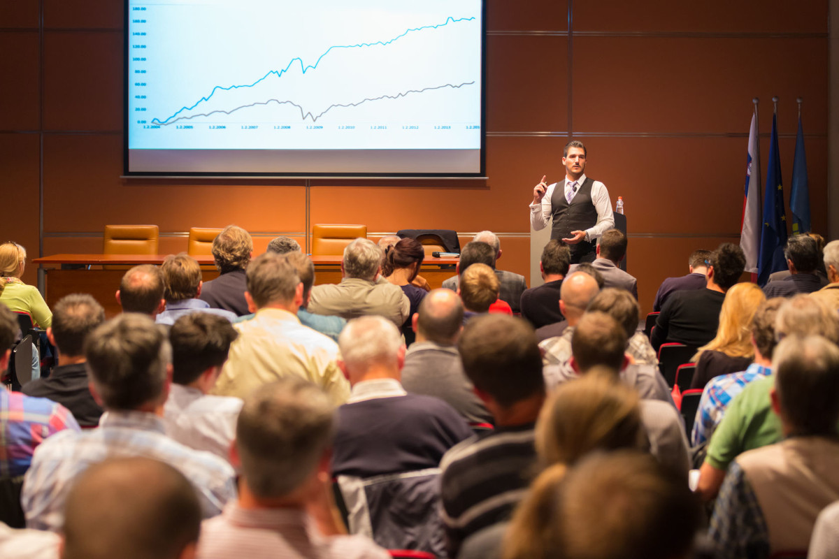 A group of people watching a businessman give a presentation