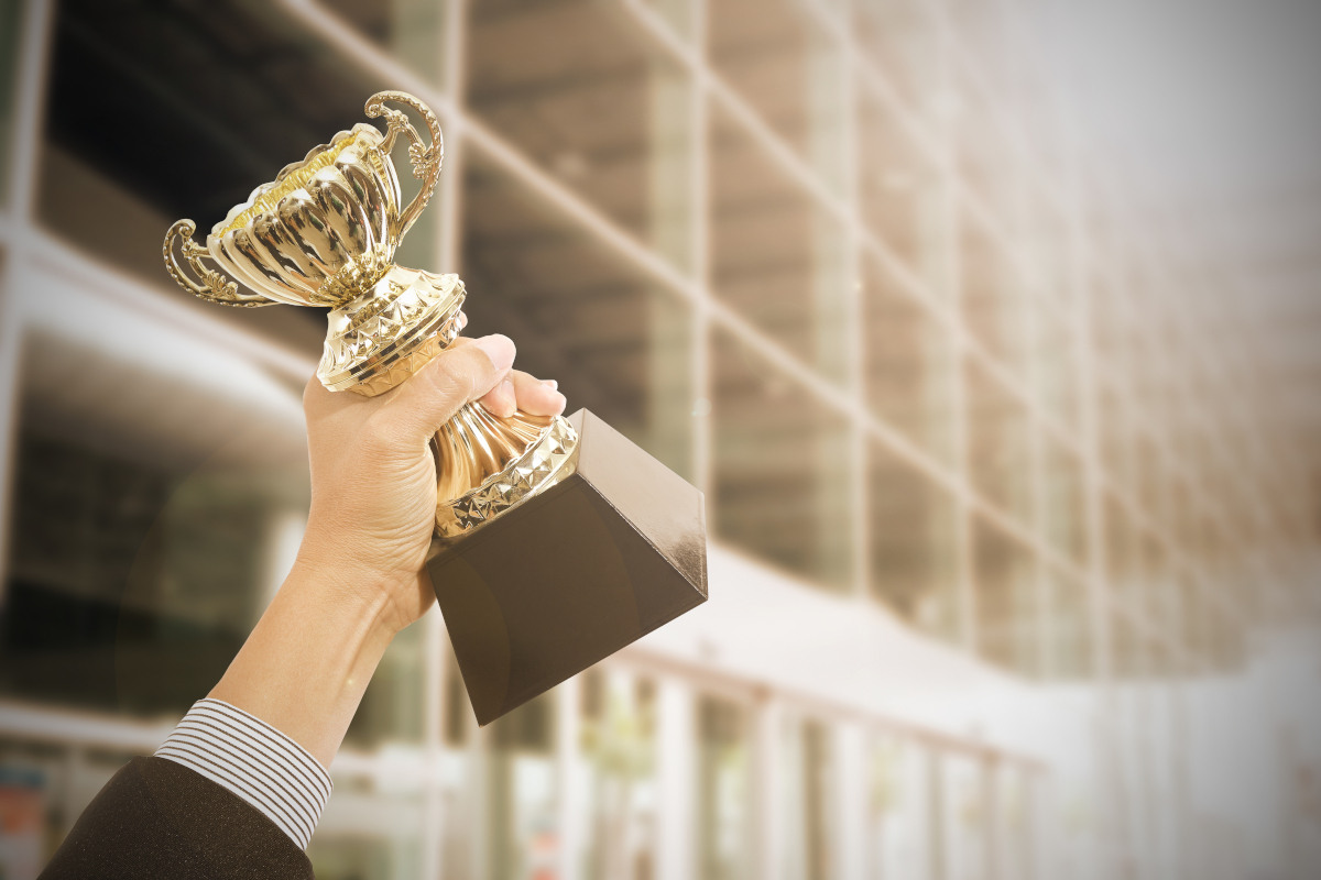 A hand holding up an award trophy triumphantly